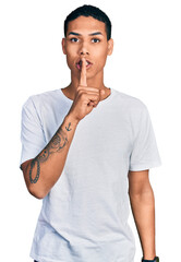 Fototapeta na wymiar Young hispanic man wearing casual white t shirt asking to be quiet with finger on lips. silence and secret concept.