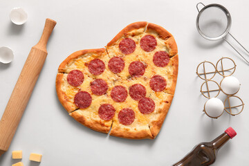 Tasty heart shaped pizza and ingredients on grey background