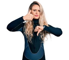 Young blonde woman wearing diver neoprene uniform doing thumbs up and down, disagreement and agreement expression. crazy conflict