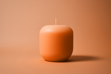A simple unlit peach fuzz color candle on minimal background. Modern trendy tone hue shade