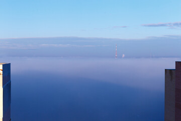 Sunrise, thick low fog, blue sky, TV tower in the fog.