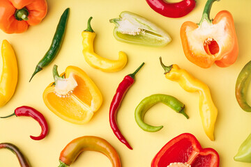 Different fresh peppers on yellow background