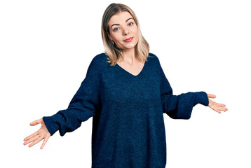 Young blonde woman wearing casual sweater clueless and confused expression with arms and hands...