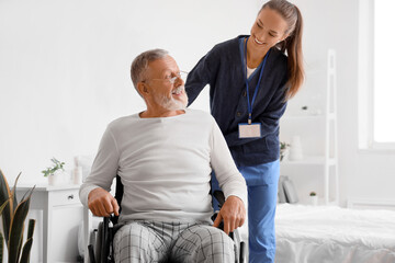 Senior man in wheelchair with caregiver at home