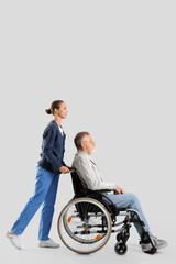 Fototapeta na wymiar Senior man in wheelchair with nurse on light background