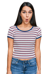 Obraz premium Young hispanic girl wearing casual striped t shirt afraid and shocked with surprise expression, fear and excited face.