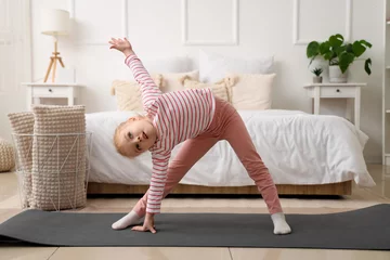 Tuinposter Cute little girl doing gymnastics on mat in bedroom © Pixel-Shot