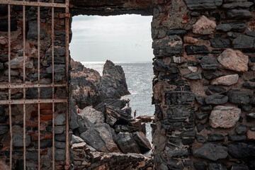 stone window or opening in a stone wall overlooking scenic landscape of ligurian sea and rocky...