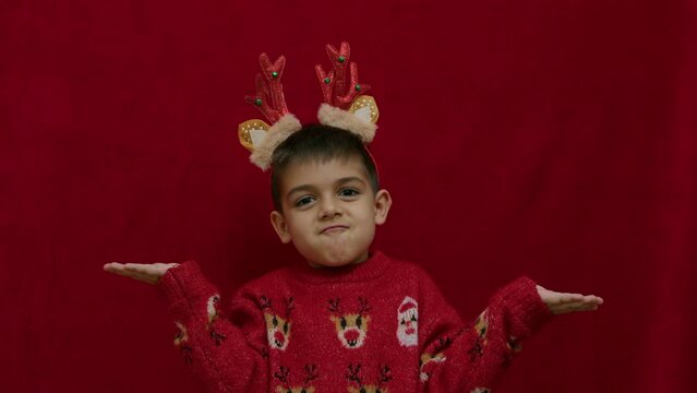 No idea. Helpless hand gesture of cute child in christmas ugly sweater and with reindeer ears and horns. having no ideas, feeling uncertain. High quality 4k footage