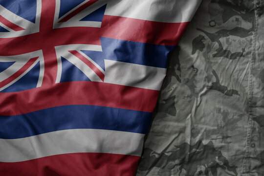 waving flag of hawaii state on the old khaki texture background. military concept.