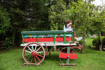 Happy child playing in old wagon on green grass
