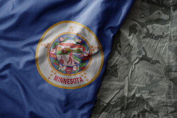 waving flag of minnesota state on the old khaki texture background. military concept.