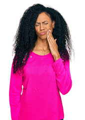 Middle age african american woman wearing casual clothes touching mouth with hand with painful expression because of toothache or dental illness on teeth. dentist