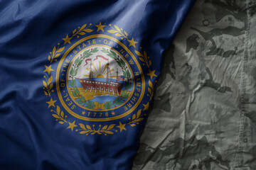 waving flag of new hampshire state on the old khaki texture background. military concept.