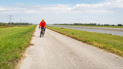 Obraz premium senior athletic man is riding a gravel touring bike - biking on a levee trail along Chain of Rocks Canal near Granite City in Illinois