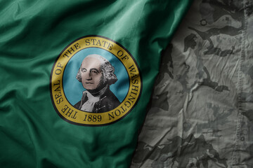 waving flag of washington state on the old khaki texture background. military concept.