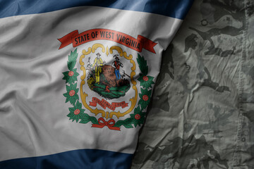 waving flag of west virginia state on the old khaki texture background. military concept.