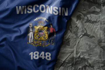 Fototapeta na wymiar waving flag of wisconsin state on the old khaki texture background. military concept.