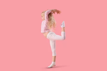 Fotobehang Cute little girl doing gymnastic exercises on pink background © Pixel-Shot