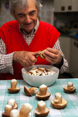 Fototapeta na wymiar Senior Man Enjoy Cleaning Porcini Mushrooms at Home with Porcelain Kitchen Knife