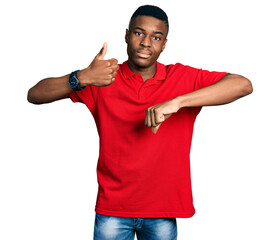 Young african american man wearing casual red t shirt doing thumbs up and down, disagreement and agreement expression. crazy conflict