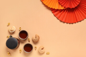 Teapot with cups of tea, fortune cookies and Chinese symbols on beige background. New Year...