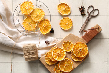 Wooden board and stand with dried orange slices on white tile background