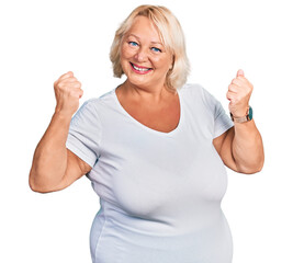 Middle age blonde woman wearing casual white t shirt very happy and excited doing winner gesture with arms raised, smiling and screaming for success. celebration concept.