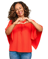 Middle age hispanic woman wearing casual clothes smiling in love showing heart symbol and shape...