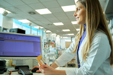 young pharmacist girl dispensing a medicine on the computer in a pharmacy