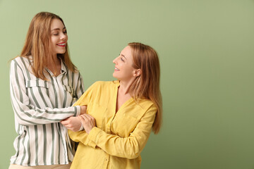 Beautiful young woman and her mother on green background. International Hug Day