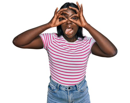 African young woman wearing casual striped t shirt doing ok gesture like binoculars sticking tongue out, eyes looking through fingers. crazy expression.