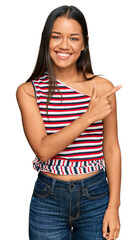 Beautiful hispanic woman wearing casual clothes cheerful with a smile of face pointing with hand and finger up to the side with happy and natural expression on face