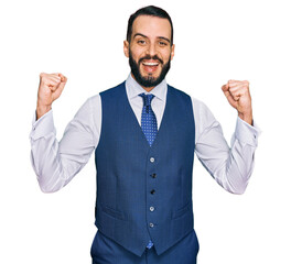 Young man with beard wearing business vest celebrating surprised and amazed for success with arms raised and open eyes. winner concept.