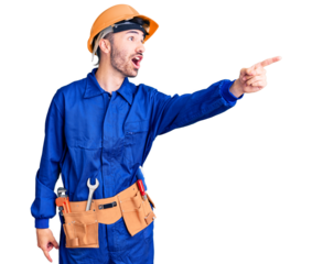 Young hispanic man wearing worker uniform pointing with finger surprised ahead, open mouth amazed expression, something on the front