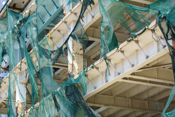 Protective mesh on scaffolding torn by hurricane wind. Background with selective focus