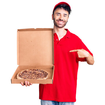 Young hispanic man holding delivery pizza box pointing finger to one self smiling happy and proud