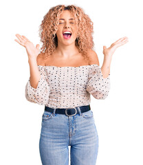 Young blonde woman with curly hair wearing casual clothes celebrating mad and crazy for success...
