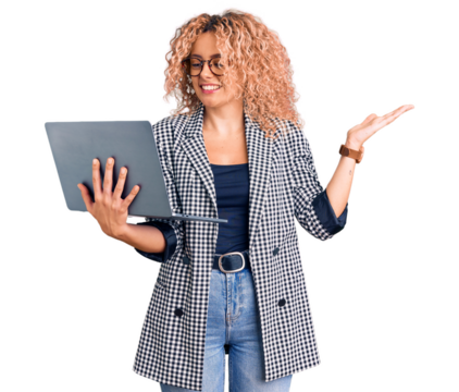 Young blonde woman with curly hair working using laptop celebrating victory with happy smile and winner expression with raised hands