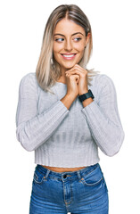 Beautiful blonde woman wearing casual clothes laughing nervous and excited with hands on chin looking to the side