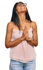 Young african american woman wearing casual clothes and glasses begging and praying with hands together with hope expression on face very emotional and worried. begging.