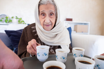 Cheerful arabian old woman is offered a cup of coffee as a hospitality
