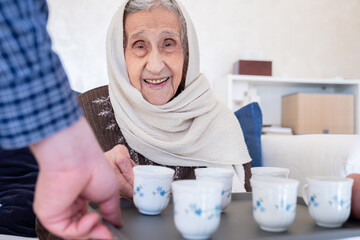 Cheerful arabian old woman is offered a cup of coffee as a hospitality