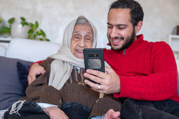 male showing smart phone to his muslim grandmother