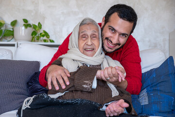 young male hugging his grandmother on sofa in modern living room