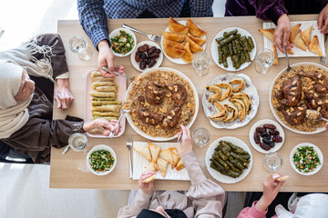 Top view for Arabian family having dinner together on wooden table with father,mother,grandfather,grandmother and son