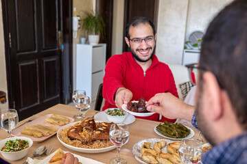 Fototapeta na wymiar Young male eating dates on dining table with his family during iftar, giving dates
