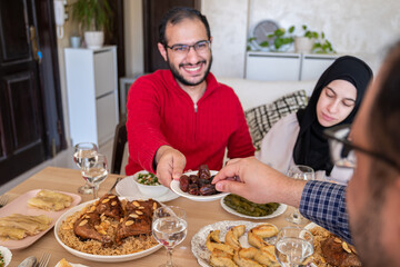 Young male eating dates on dining table with his family during iftar, giving dates