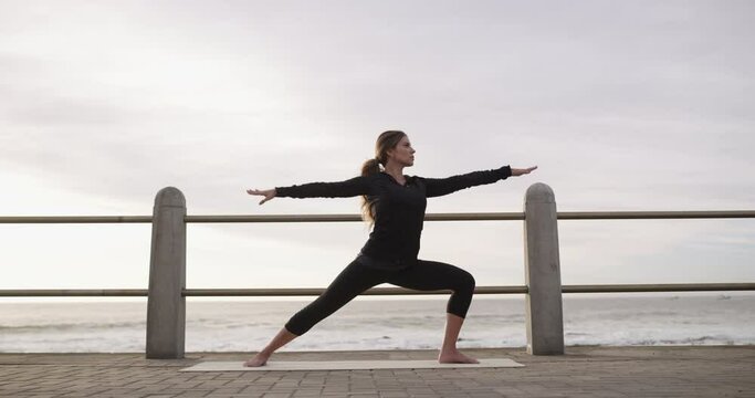Warrior pose, woman and yoga at beach, fitness and exercise on promenade, zen and mindfulness. Female person, meditation and spiritual awareness at ocean, balance and stretching for wellness at sea