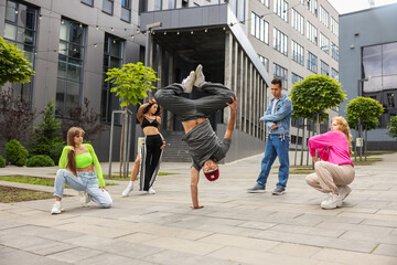 Group of people dancing hip hop outdoors, low angle view